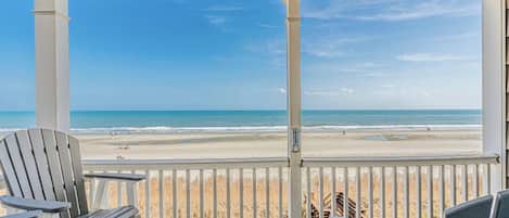 Un espace extérieur abrité avec deux fauteuils Adirondack donnant sur une plage.
