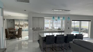 Una cucina moderna con isola centrale, ampie finestre e vista su una piscina.