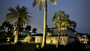 Un edificio a più piani con un ingresso luminoso e palme sullo sfondo.