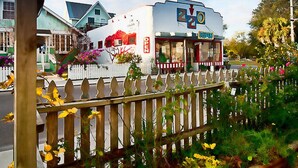 A restaurant with a white exterior and a red and white fence in front.