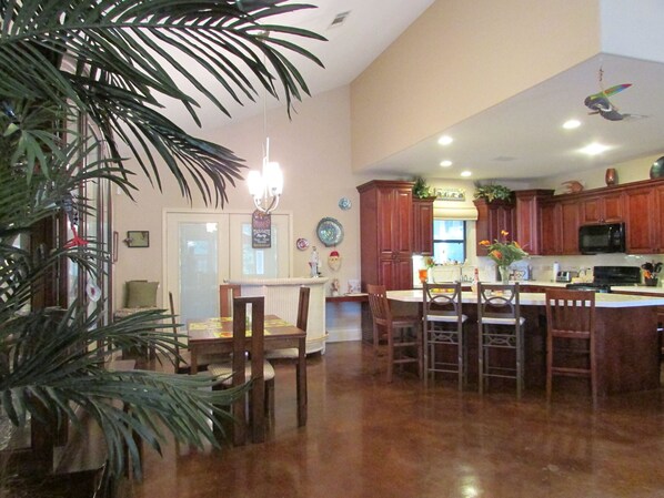 A spacious kitchen with wooden cabinets, a central island, and a dining area with chairs. - Custom Home-great weekly rates! (Bay St Louis)