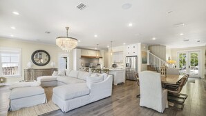 A spacious living room with a large sectional sofa, a dining area with a wooden table and chairs, and a kitchen with modern appliances.