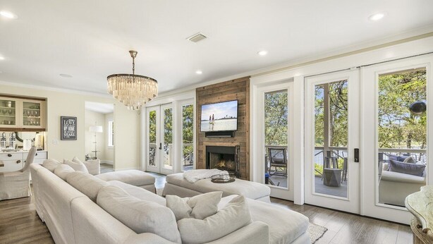 A spacious living room with a large sectional sofa, a fireplace, and a television mounted on a wooden wall.