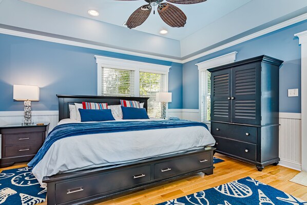 A bedroom with a bed, nightstands, a dresser, and a ceiling fan.