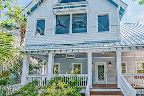 A two-story house with a porch, multiple windows, and a door.
