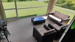 A patio area with a grill, a sofa, and a coffee table. - New Modern Vacation Home on a budget! Smart TV only. NO CABLE (Lehigh Acres)