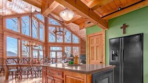 A spacious kitchen with large windows, wooden cabinets, and a black refrigerator. - Serenity Retreat (Formerly Leins Lodge) Luxury Home Stunning Mountain Views (Maggie Valley)