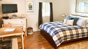 Une chambre à coucher comprenant un lit, un bureau, une chaise, un téléviseur et un ventilateur de plafond.