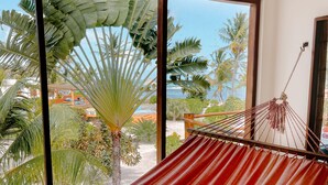 Una cadira de cadenes en una habitació amb grans finestres que donen vistes a una piscina i palmeres.