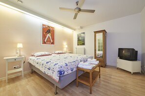 Ein Schlafzimmer mit Bett, Nachttischlampen, Deckenventilator, Fernseher und Spiegel.