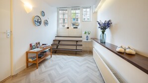 A hallway with a wooden bench, a radiator, and a small table with books.