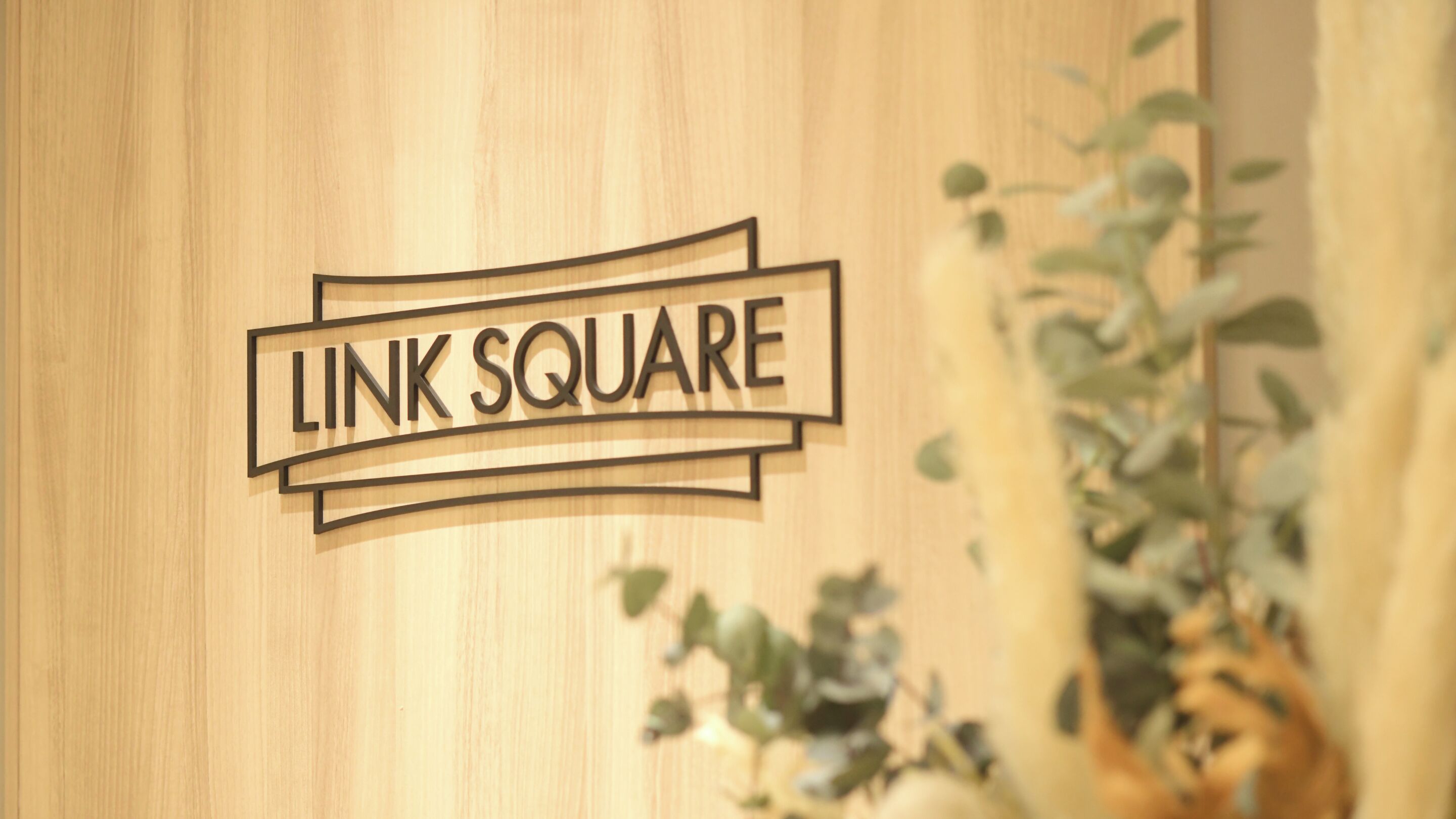 Pared de madera con el texto "LINK SQUARE" en una tipografía estilizada.