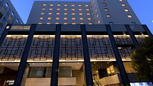 A modern hotel building with multiple floors, a prominent sign for the Oriental Hotel, and a Starbucks coffee shop at the ground level. - Oriental Hotel Fukuoka Hakata Station (Fukuoka)