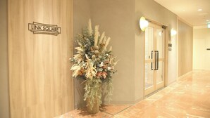 A hallway with a sign reading "LINK SQUARE," a potted plant with dried flowers, and a door with a glass panel and a sign above it. - Oriental Hotel Fukuoka Hakata Station (Fukuoka)
