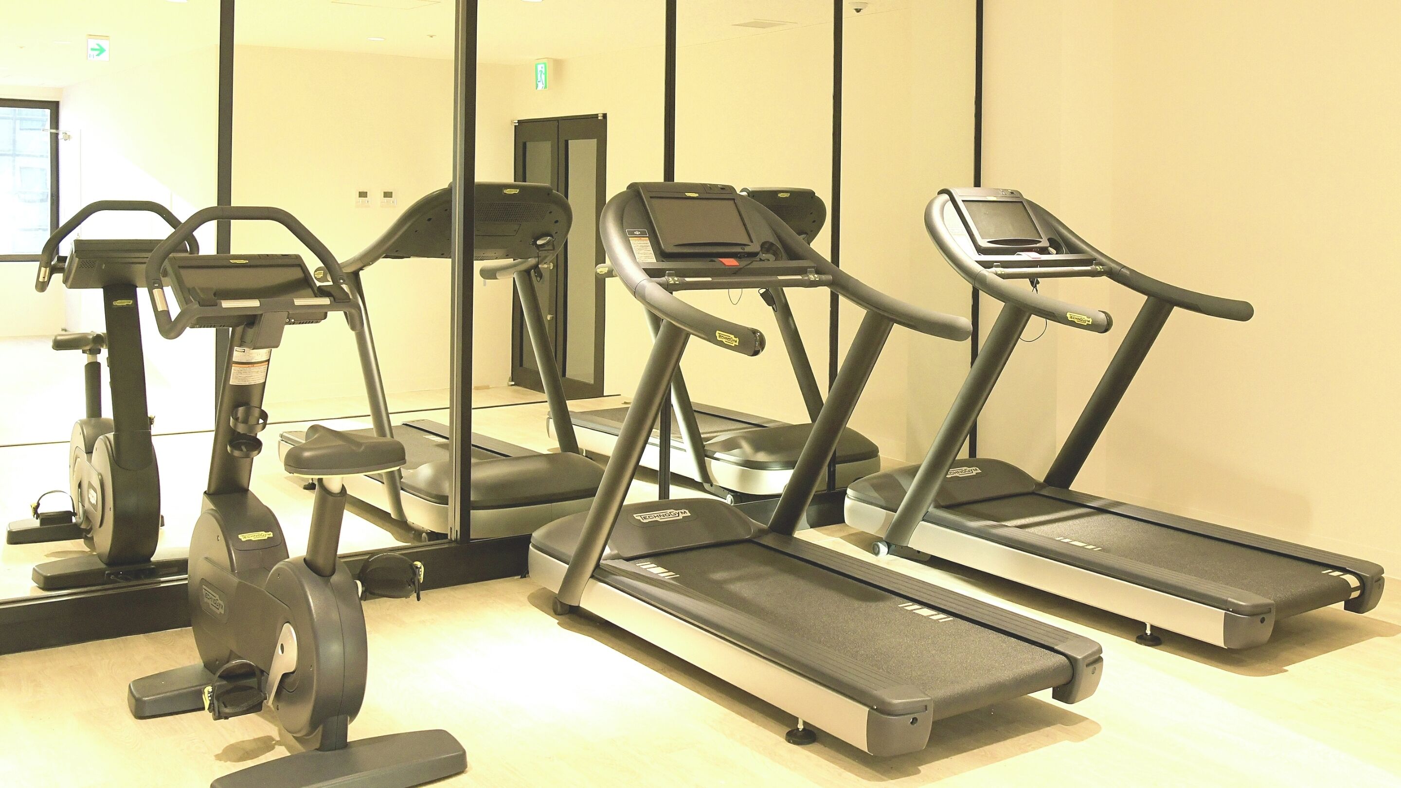 Une salle de sport équipée de vélos d’appartement, de machines elliptiques et de tapis de course.