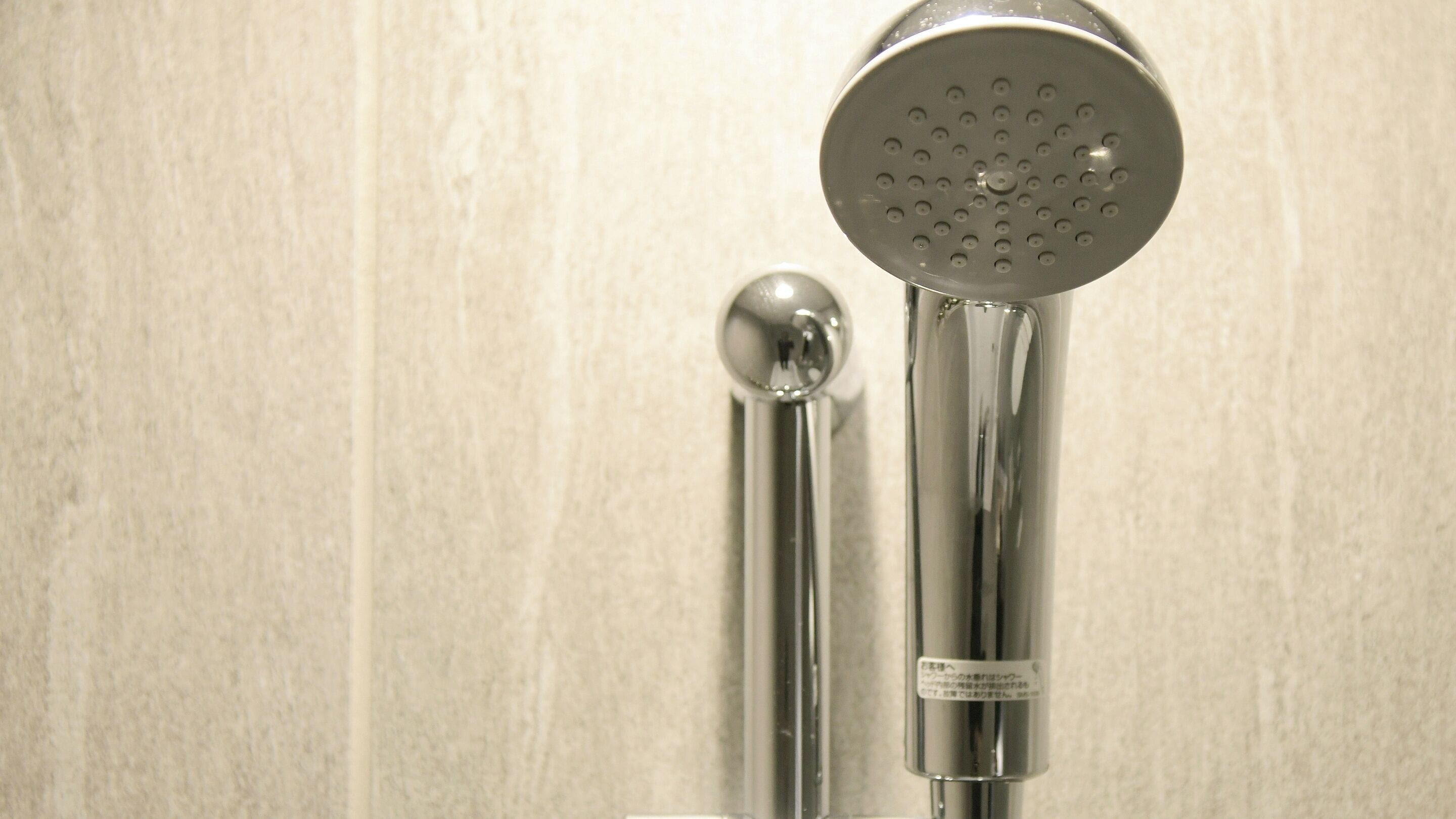 Un pommeau de douche et un flexible de douche fixé au mur.