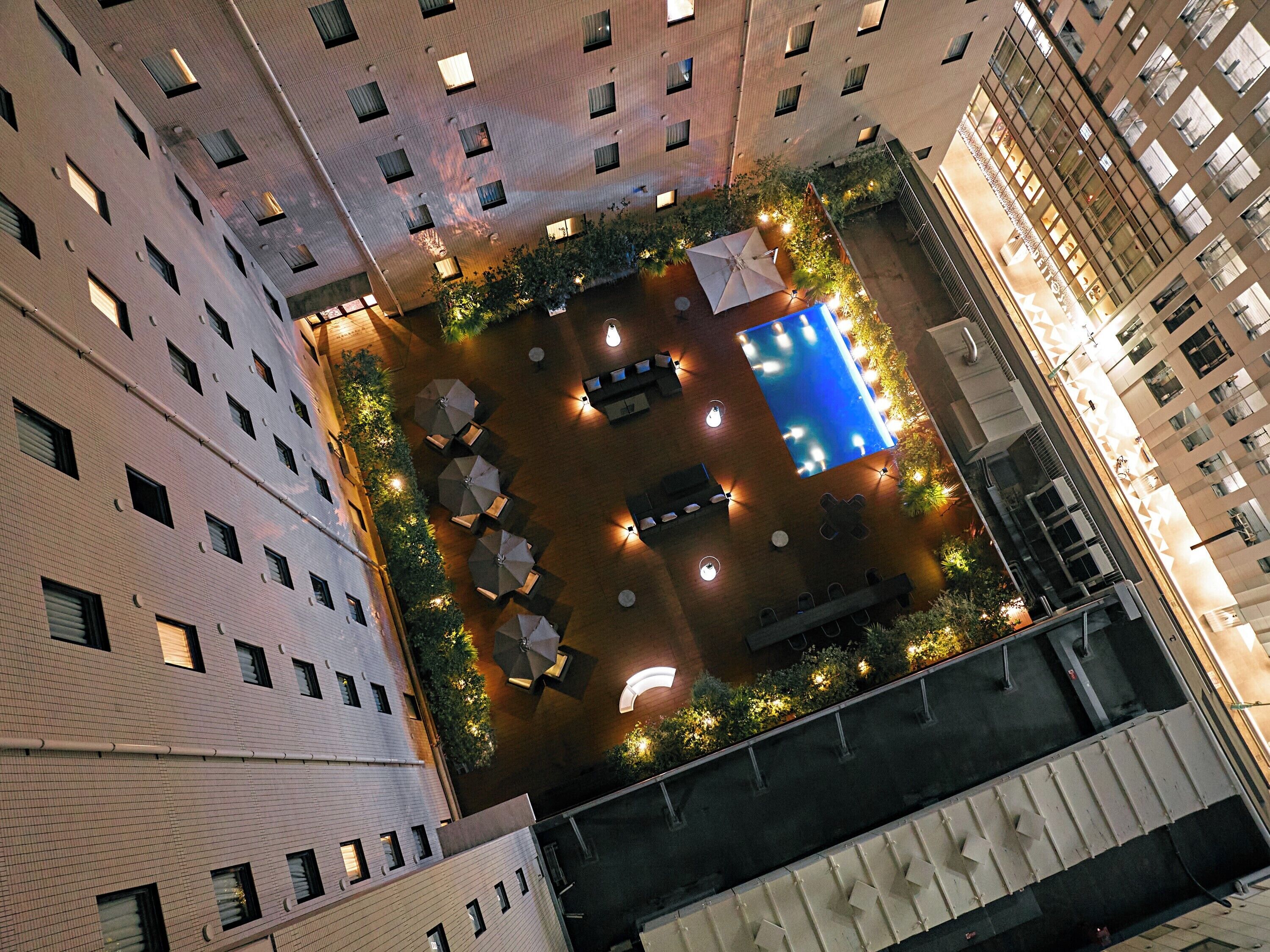 A rooftop pool area surrounded by multiple-story buildings with balconies.