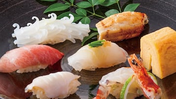 A variety of sushi on a black plate, including salmon, tuna, and shrimp.