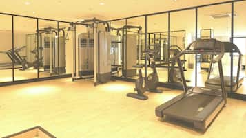 A gym with cardio machines, weight training equipment, and a mirrored wall.