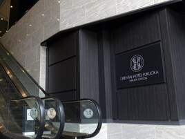 Una escalera mecánica en un edificio moderno con un cartel del Hotel Oriental Fukuoka Hakata Station.