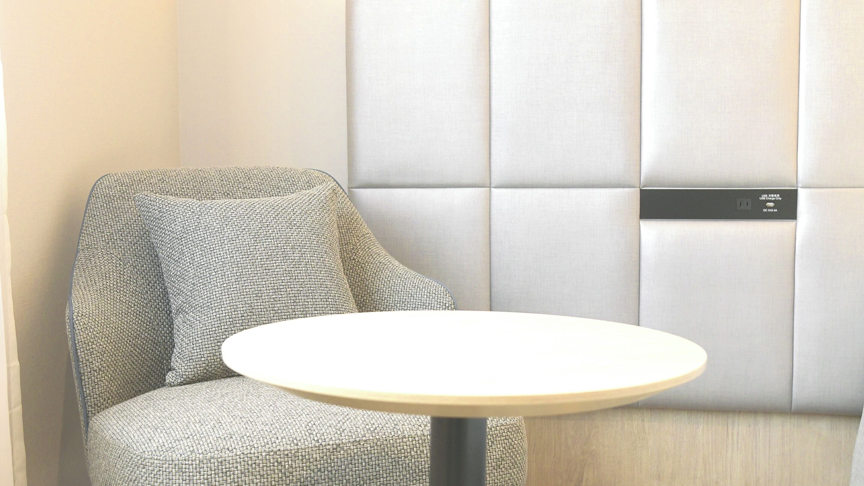 A corner of a room with a cushioned seating area and a small round table.