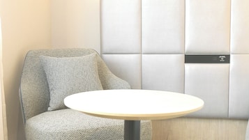 A corner of a room with a cushioned seating area and a small round table.