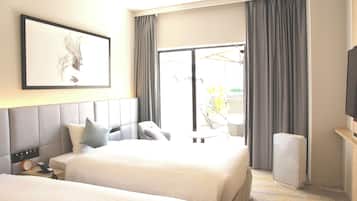 A hotel room with two beds, a large window with curtains, a flat-screen TV, and a framed artwork on the wall.
