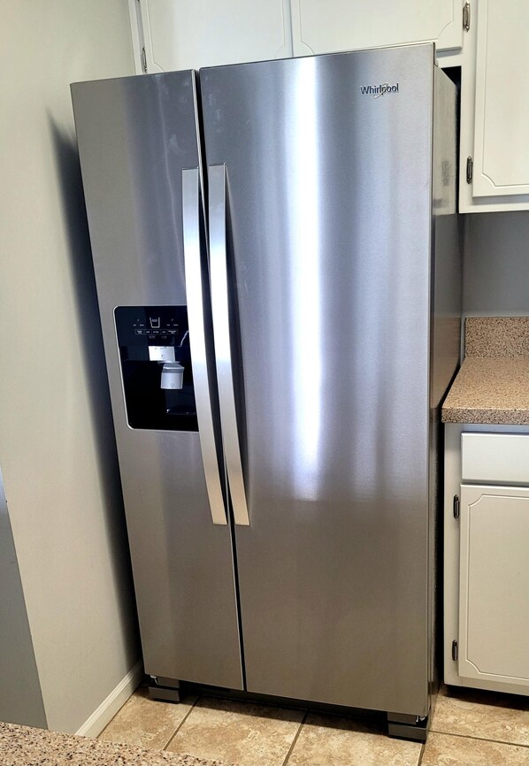 Ein Edelstahl-Kühlschrank von Whirlpool mit einem linksseitigen Gefrierfach, einem Wasserspender und einem integrierten Eisbereiter.