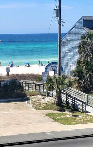 A beach with a wooden building, a lifeguard tower, and a sign for the beach public.