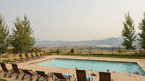 Une piscine dotée de chaises longues et offrant une vue sur les montagnes lointaines.
