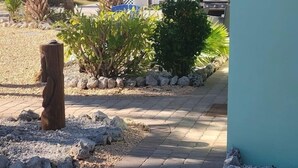 A paved pathway leading to a building with a light green exterior, surrounded by palm trees and a clear sky. - For those who want ONLY THE BEST!  60 Steps to the Beach - Gulf Views! (Manasota Key)