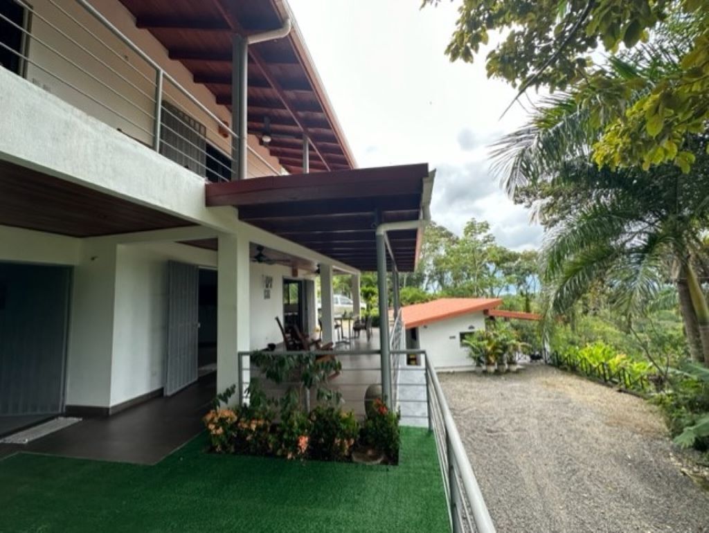 Un bâtiment à deux étages doté d’un espace extérieur couvert, d’un chemin de gravier et d’un aménagement paysager environnant.