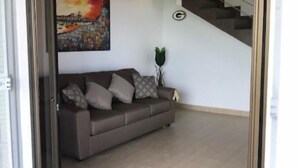 A modern living room with a sofa, a painting, and a staircase.