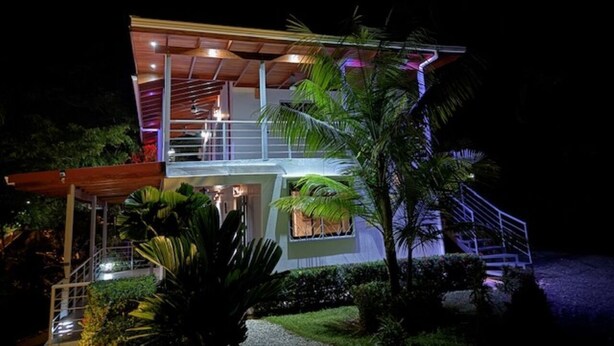 A modern two-story house with a balcony, a staircase, and a well-lit entrance.