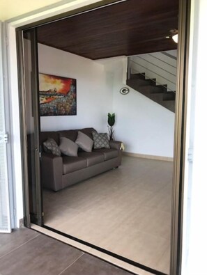 Una sala de estar moderna con un sofá, un cuadro y una escalera.