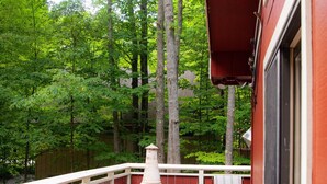 Une terrasse en bois avec une cheminée, un banc et un bâtiment rouge.