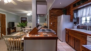 Eine Küche mit einer zentralen Kochinsel, einem Kühlschrank und Holzschränken.