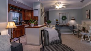 Ein geräumiges Wohnzimmer mit Sofa, Essbereich mit Tisch und Küchenzeile mit Holzschränken und Kühlschrank.
