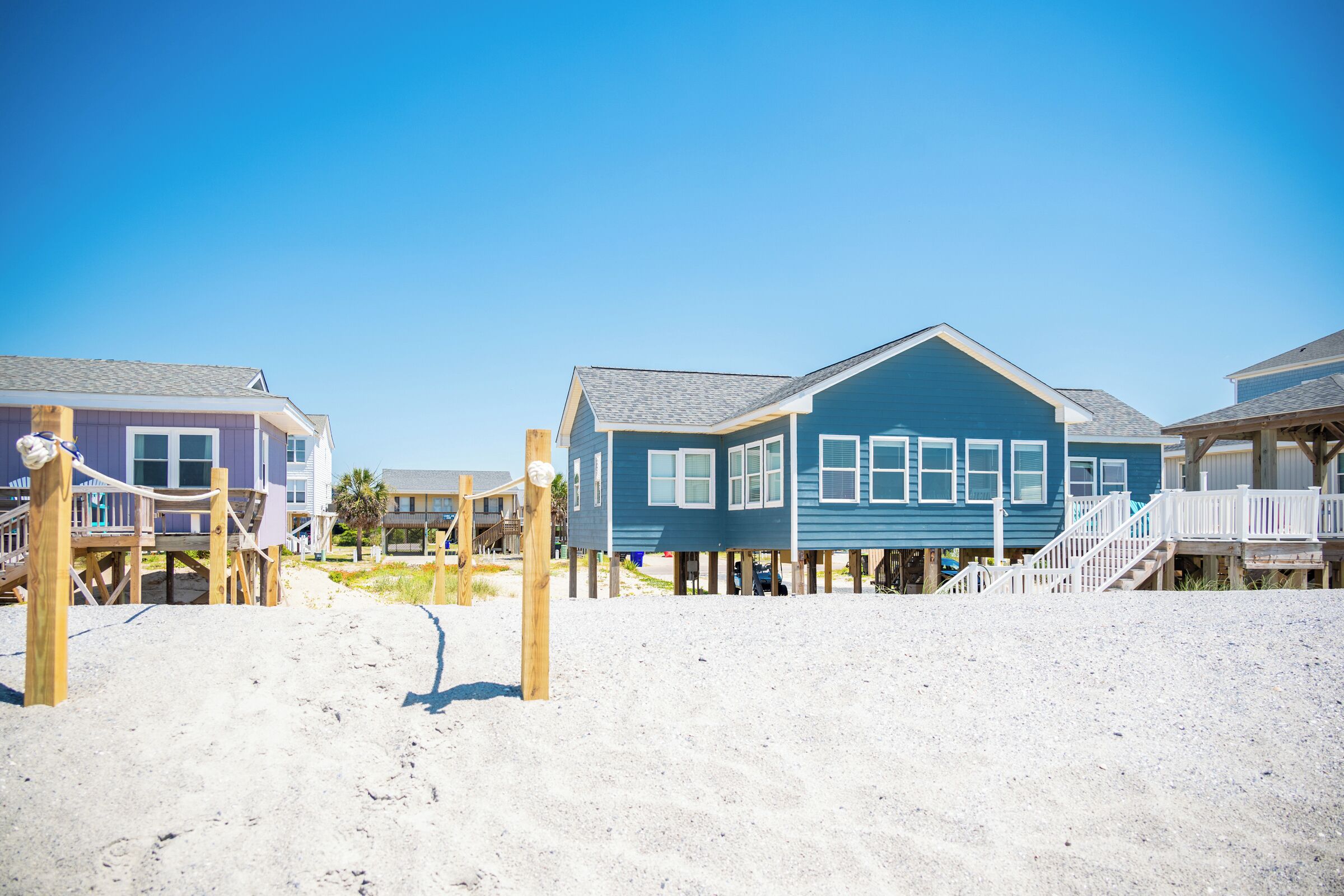 A beachfront property with wooden walkways and a blue house.