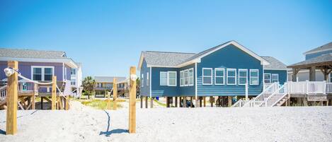 A beachfront property with wooden walkways and a blue house.