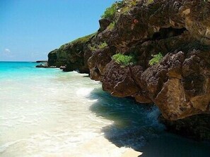 A rocky coastline with clear turquoise water and a sandy beach. - Hidden Gem in Esperanza--Easy Walk to Waterfront, Restaurants, Shops & Beach (Vieques)