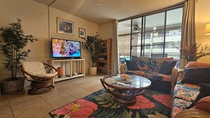 Een woonkamer met een televisie, een bank, een fauteuil en een salontafel.