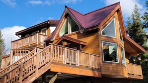 Een houten chalet met meerdere verdiepingen, een hellend dak, houten balkons en grote ramen.