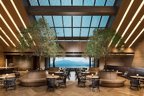 A modern interior with a central seating area, tables, and a view of mountains. - Conrad Hangzhou Tonglu (Hangzhou)