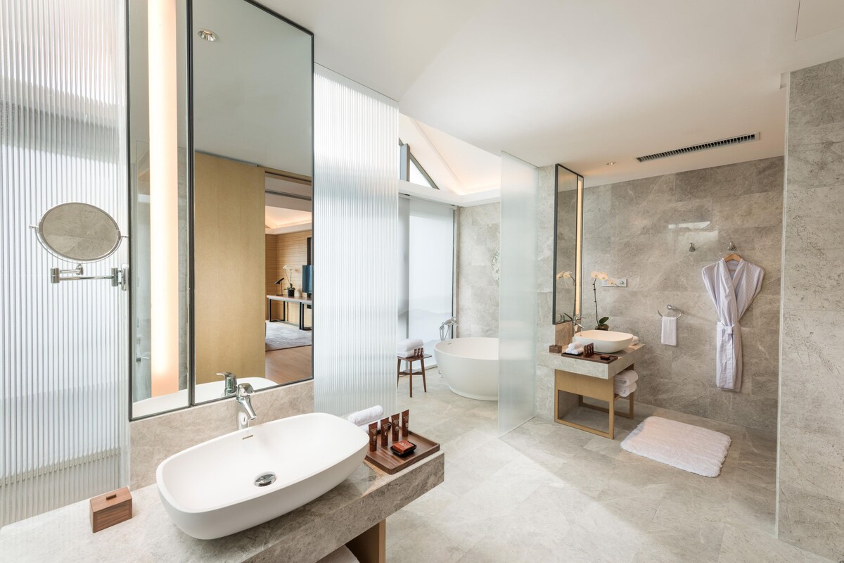 A modern bathroom with a large mirror, a freestanding bathtub, and a vanity with a sink.