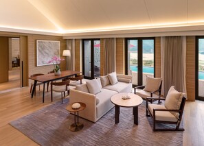 A modern hotel room with a dining area, a sofa set, a coffee table, and a view of a pool. - Conrad Hangzhou Tonglu (Hangzhou)