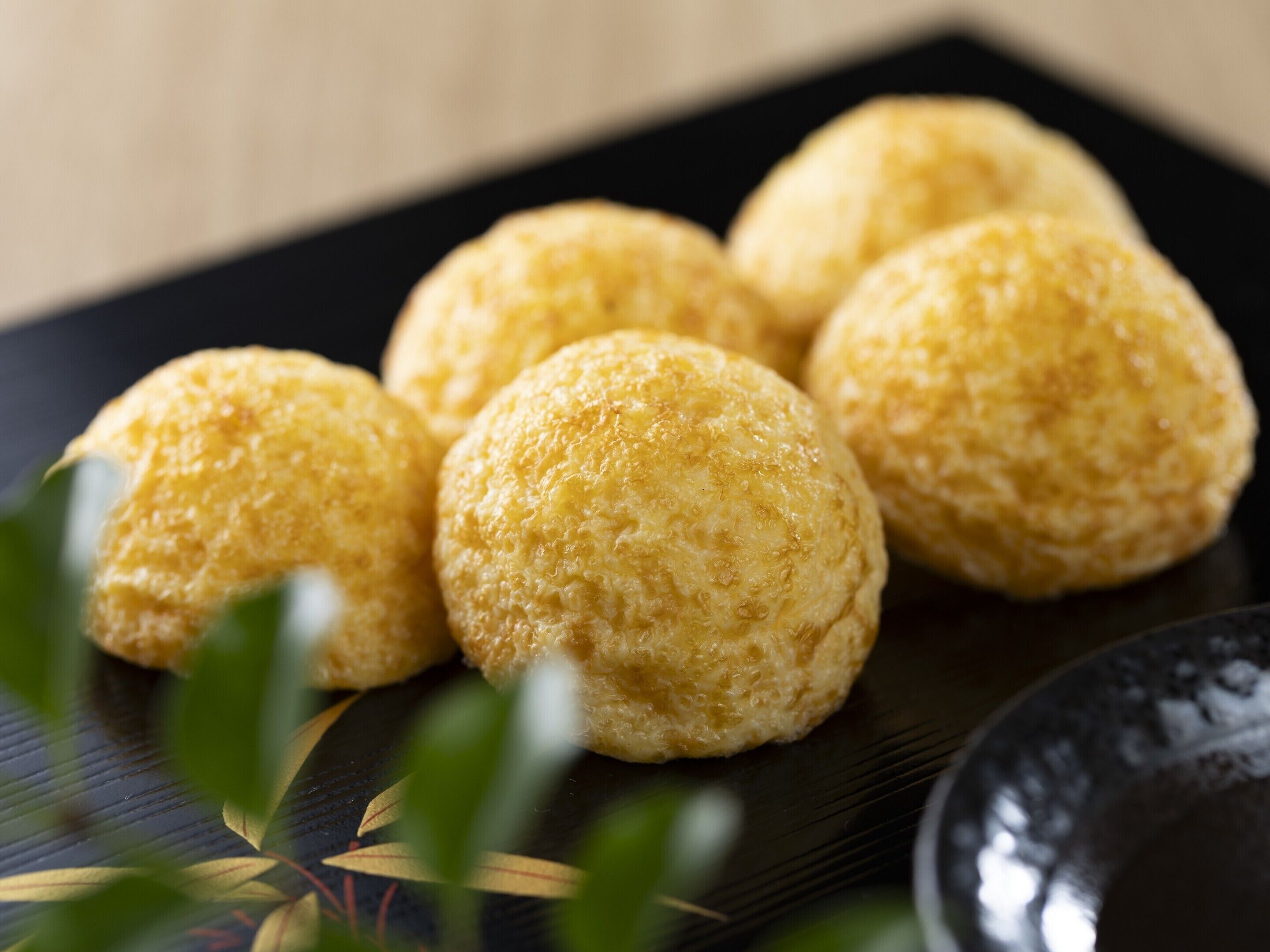 A close-up of round, golden-brown pastries on a black plate.
