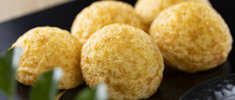 A close-up of round, golden-brown pastries on a black plate.