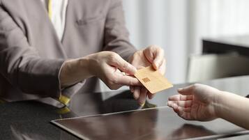 A person handing over a card to another person at a counter.