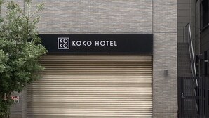 Letrero de hotel con el nombre 'KOKO HOTEL' en la fachada de un edificio moderno.